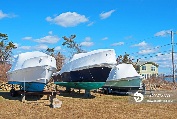 Three boats are stored for the winter in Fairhaven, Massachusetts, out of the water and on blocks wi