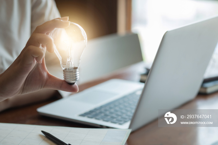 woman hands holding light bulb in working place.