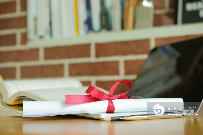 close up bachelors degree certificate on laptop with book in the library for online learning gradua