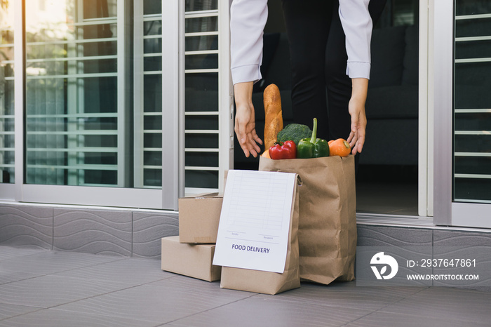 Asian woman open the door and took the bag of food ordered by the carrier to put in front of the hou