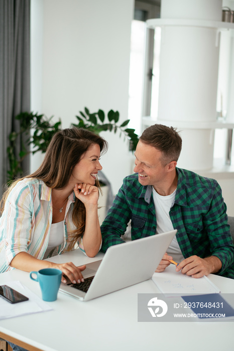 Husband and wife preparing bills to pay. Young couple using laptop.