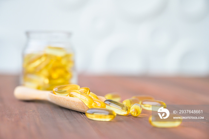 Pile of capsules Omega 3 in glass bottle on wood table