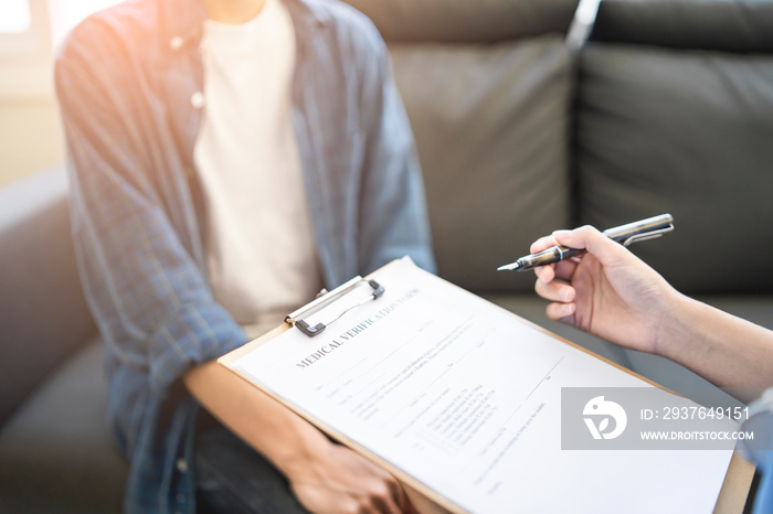 Close up asian female doctor writing and filling out forms on patient’s diagnosis information, with 