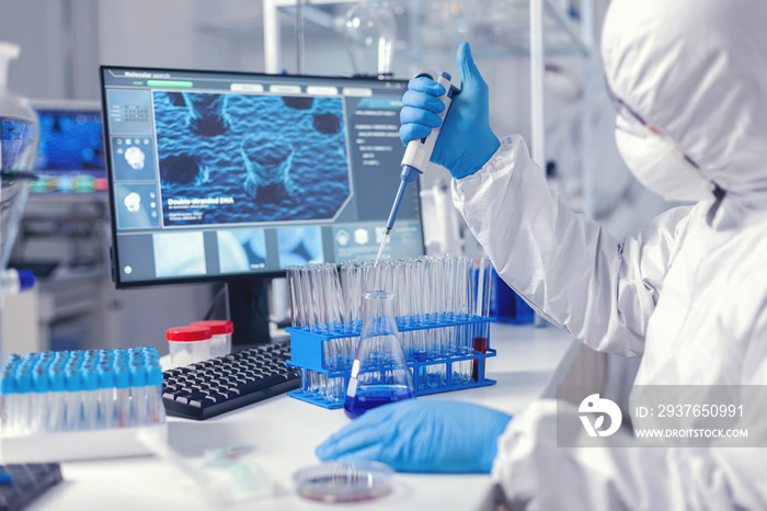 Healthcare researcher in ppe suit working with micro pipette in time of coronavirus. Chemist in mode