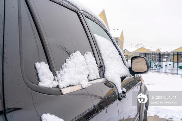 一辆闪亮的黑色汽车的外部视图，有色车窗上有新鲜的雪