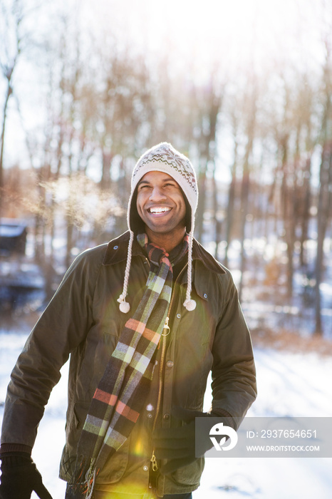 Happy man looking away while standing on snow covered field