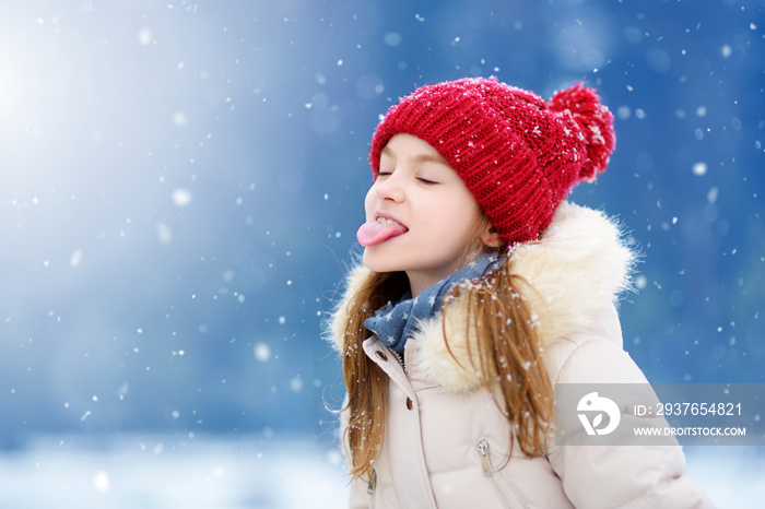 可爱的小女孩在美丽的冬季公园里用舌头捕捉雪花。可爱的孩子在玩耍