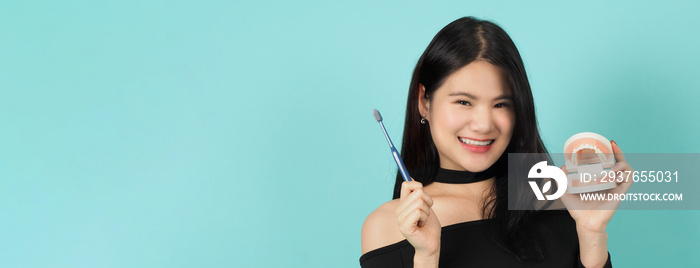 Woman holding toothbrush and dental teeth model or orthodontic model. Oral health care concept. Asia