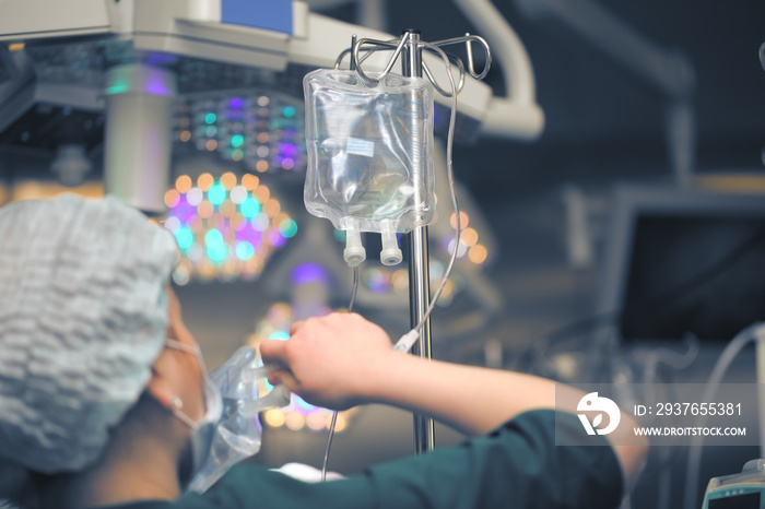 Female nurse replacing solution bags in the drip system in the operating room