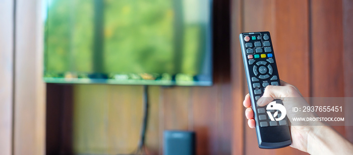 hand using remote controller for adjust Smart TV inside the modern room at home or luxury hotel