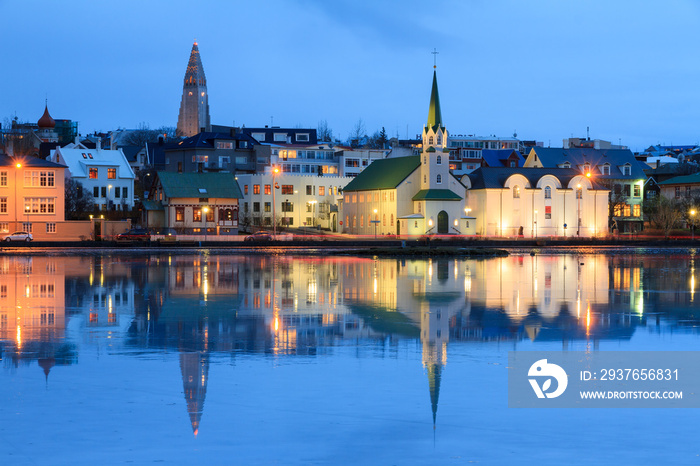 Beautiful reflection of the cityscape of Reykjavik in lake Tjornin at the blue hour in winter