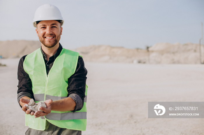 Worker in sand quarry holding rocks