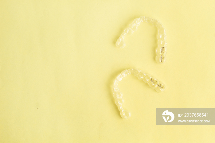 Invisible dental aligners or clear aligners on yellow background. Aesthetic orthodontic treatment pe