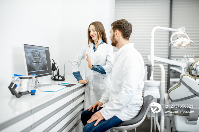 Dentist with young woman assistant working with computer in the dental office