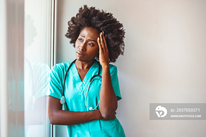 Tired female doctor near window in her office. Closeup portrait sad health care professional with he