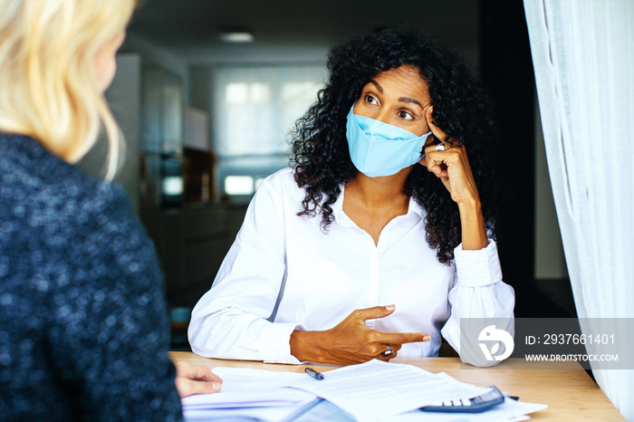 Two women having a financial business  consultation with masks and social distancing due to coronavi