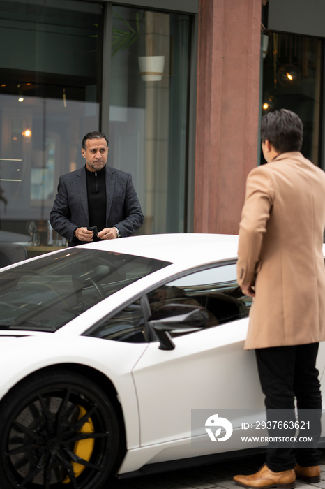 Two businessmen getting in luxury car