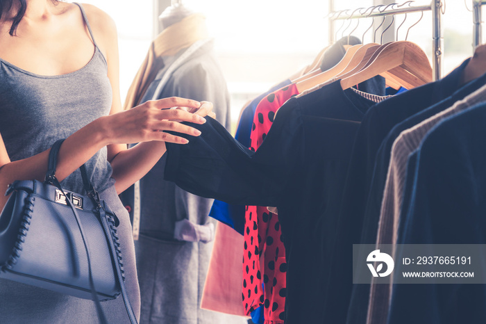 Beautiful woman shopping for clothes at retail apparel shop in the shopping mall. Modern trade lifes