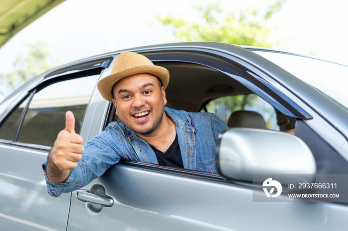 Handsome asian man wear hat the blue jeen shirt is driving and thumbs up sitting on car seat showing