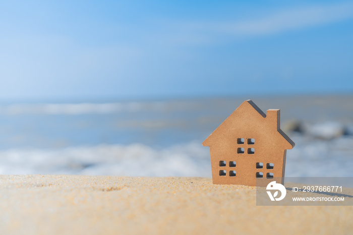 在阳光和海滩的沙滩上封闭的小型家居模型。