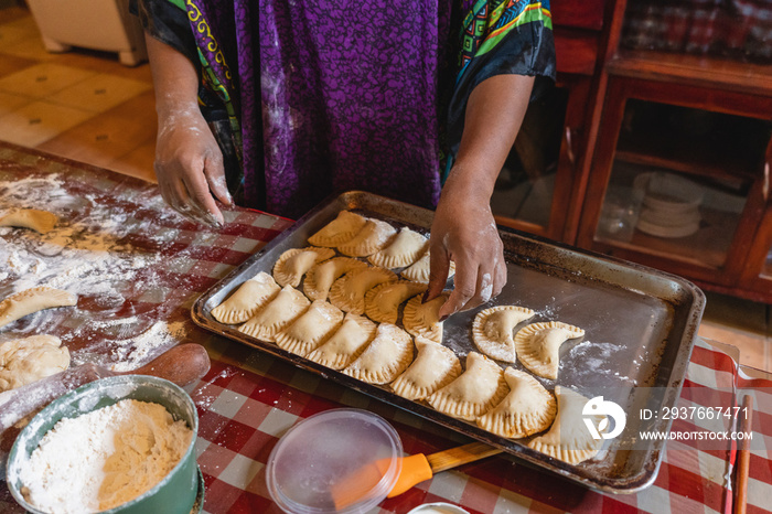 Imagen horizontal de una mujer afrocaribeña irreconocible preparando unas deliciosas empanadas en ca