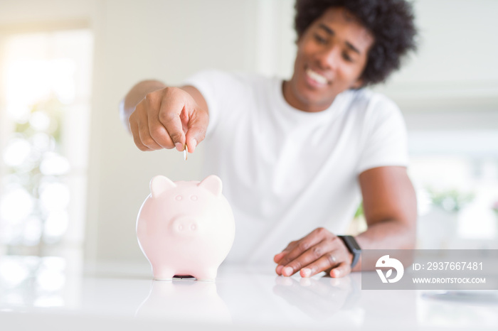 Close up of african american man saving money putting a coin inside piggy bank