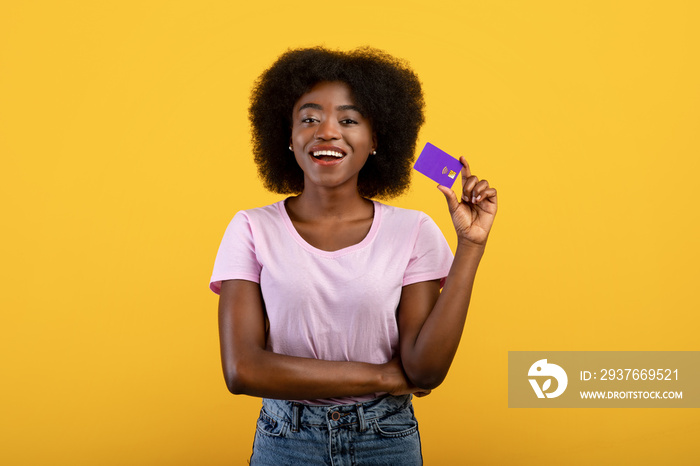 Easy payment concept. Happy young black woman holding credit card in hand and showing it to camera, 