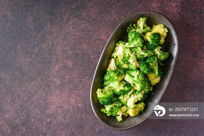 Serving dish of fresh roasted broccoli florets on a rustic background