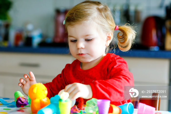 Adorable cute little toddler girl with colorful clay. Healthy baby child playing and creating toys f