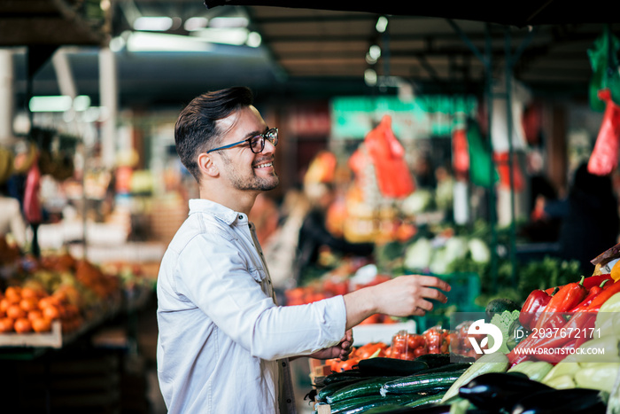 Handsome young man buying groceries at farmers market.