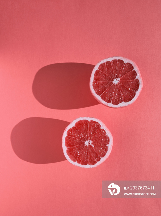 成熟的粉红色葡萄柚片，柔和的粉红色背景。柑橘类水果。现代食品极简主义概念。P