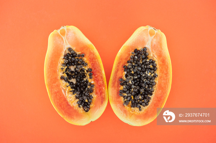 top view of ripe bright papaya halves with black seeds isolated on orange