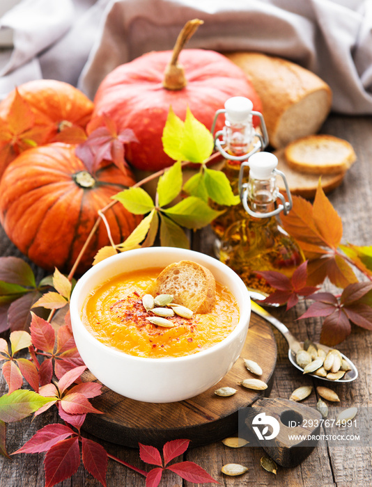 Bowl of pumpkin soup on rustic wooden background