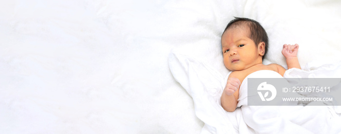 Cute newborn baby girl in white blanket on nursery bed. Adorable new born child, little boy eyes loo