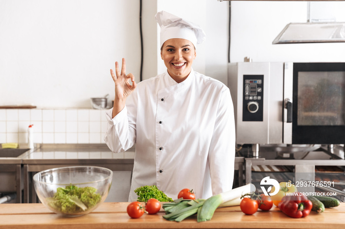 身穿白色制服的专业女厨师在厨房里用新鲜蔬菜做饭的照片