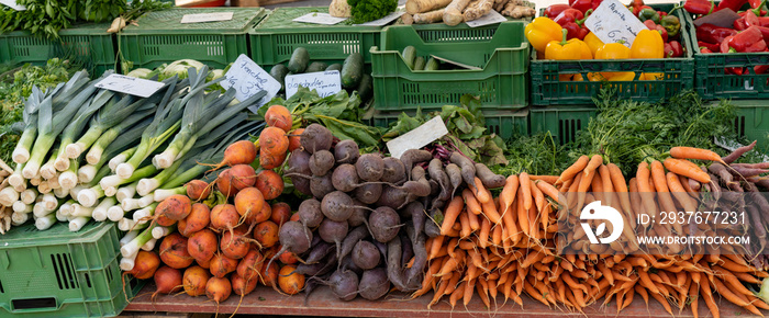 农贸市场摊位全景图，摊位上有许多有机蔬菜出售