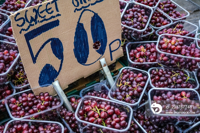 Small plastic boxes with red grapes displayed on food market at Lewisham, London