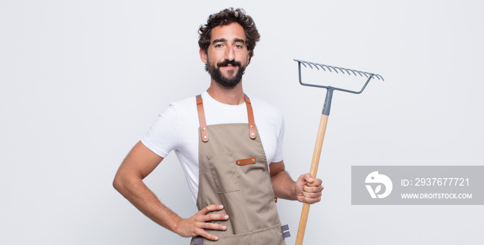 young man smiling happily with a hand on hip and confident, positive, proud and friendly attitude