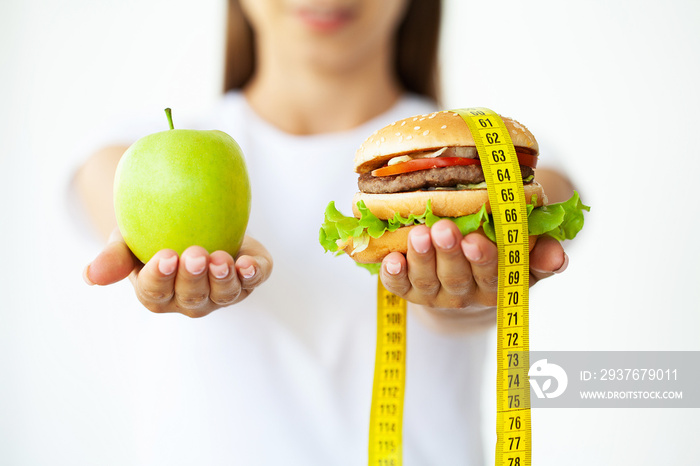 Diet concept, woman holding a choice of harmful hamburger and fresh apple.