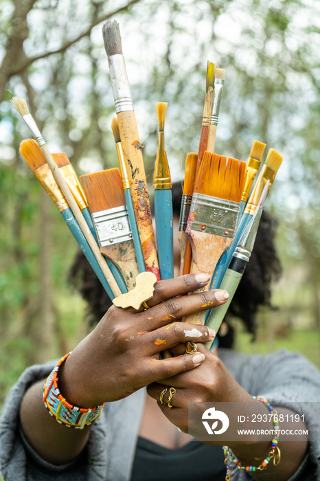 artist with brushes covering her face