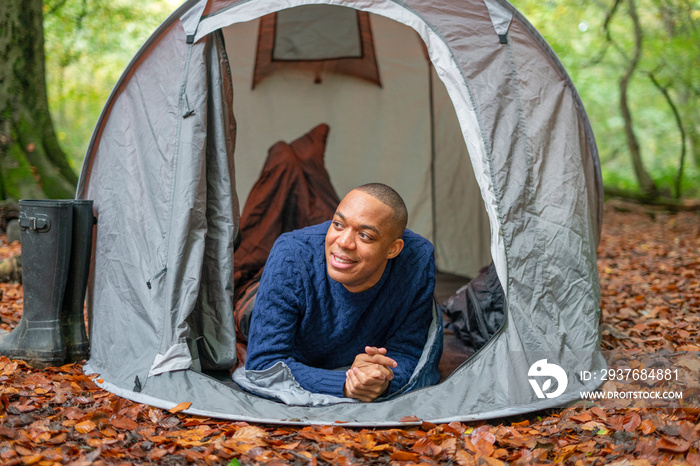 Man relaxing in tent in forest at autumn?