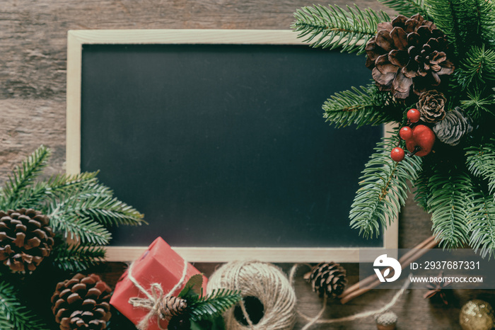 Christmas decoration with blackboard or chalkboard, pine leaves and cones, gift box and holly balls 