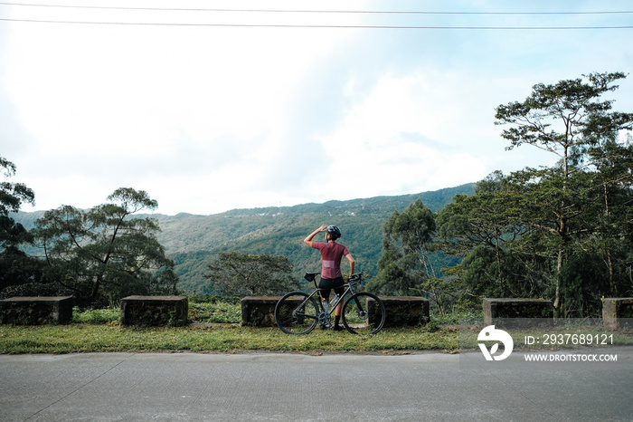 A young female cyclist looking at a view in the mountains during her bike ride.