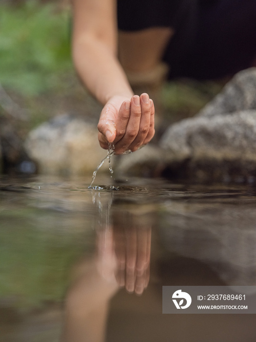 一名年轻女子触摸溪流中的水的特写图像