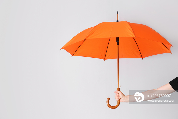 Female hand with umbrella on light background