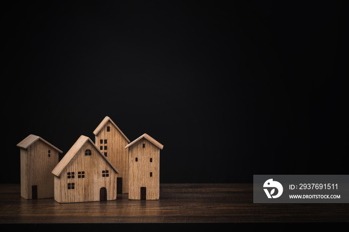 real estate concept, small wooden house or home on table with black background