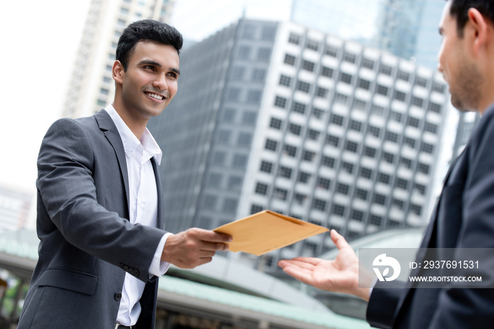 Indian businessman giving document in the envelope to his partner