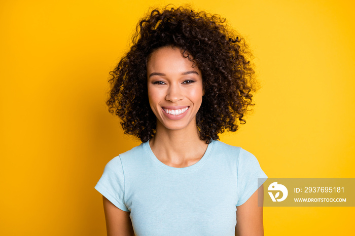 美丽的非洲裔美国卷发女孩的照片肖像，她在鲜艳的黄色背景上微笑