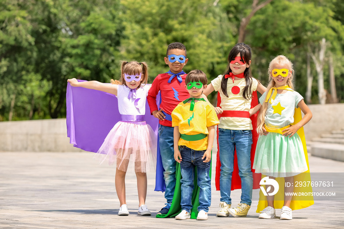 Cute little children dressed as superheroes outdoors