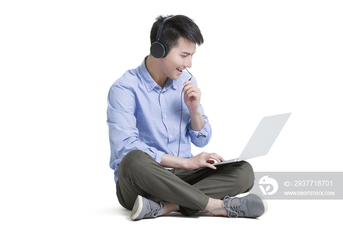 年轻男子使用笔记本电脑听音乐